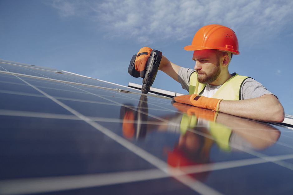 Professional solar panel installer working on a roof